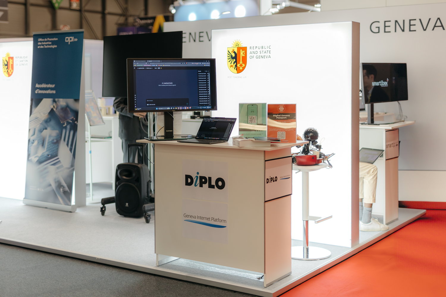 Diplo/GIP at AI for Good Global Summit 3 Furniture, Table, Desk, Computer Hardware, Electronics, Hardware, Monitor, Screen, Speaker, Person, Computer, Laptop, Pc, Face, Head