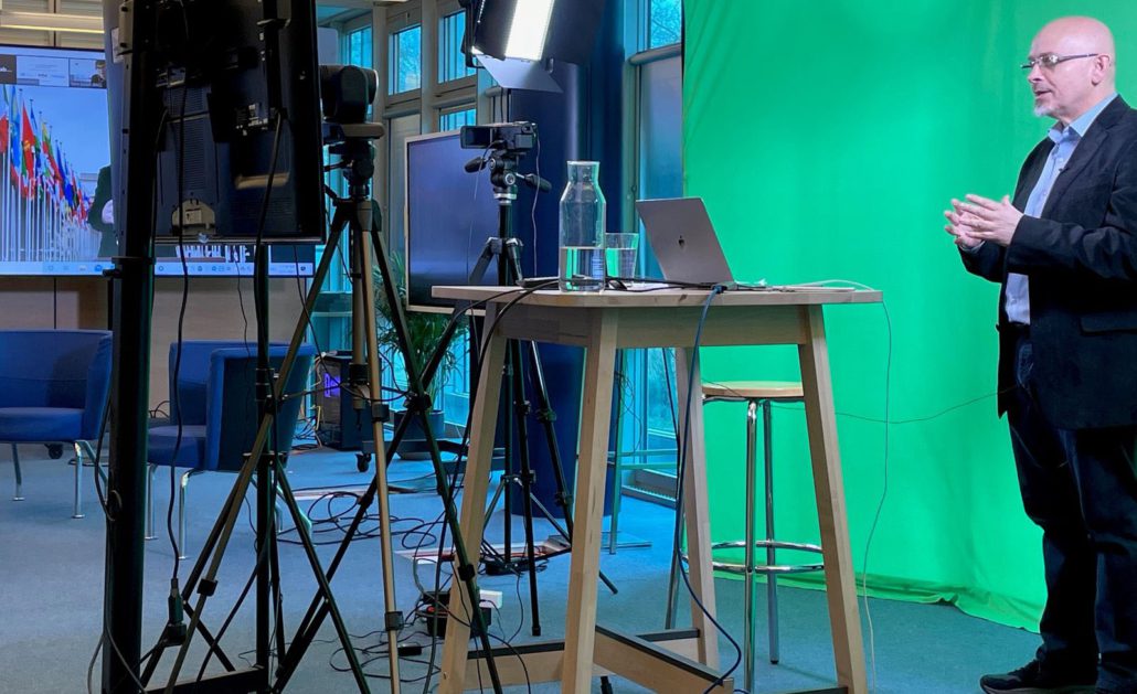 conftech-geneva-03 Furniture, Table, Desk, Adult, Male, Man, Person, Crowd, Clothing, Coat, Face, Head, Computer, Electronics, Laptop, Pc, Standing Desk