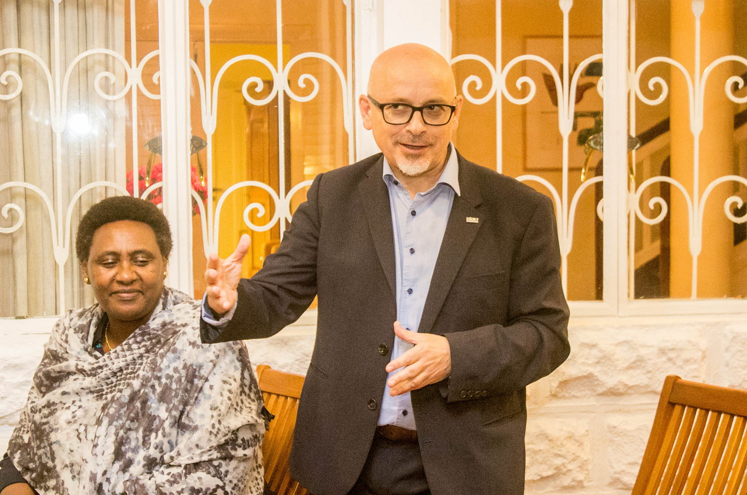  Blazer, Clothing, Coat, Jacket, People, Person, Face, Head, Photography, Portrait, Adult, Male, Man, Chair, Furniture, Accessories, Glasses, Formal Wear, Suit, Indoors, Body Part, Hand