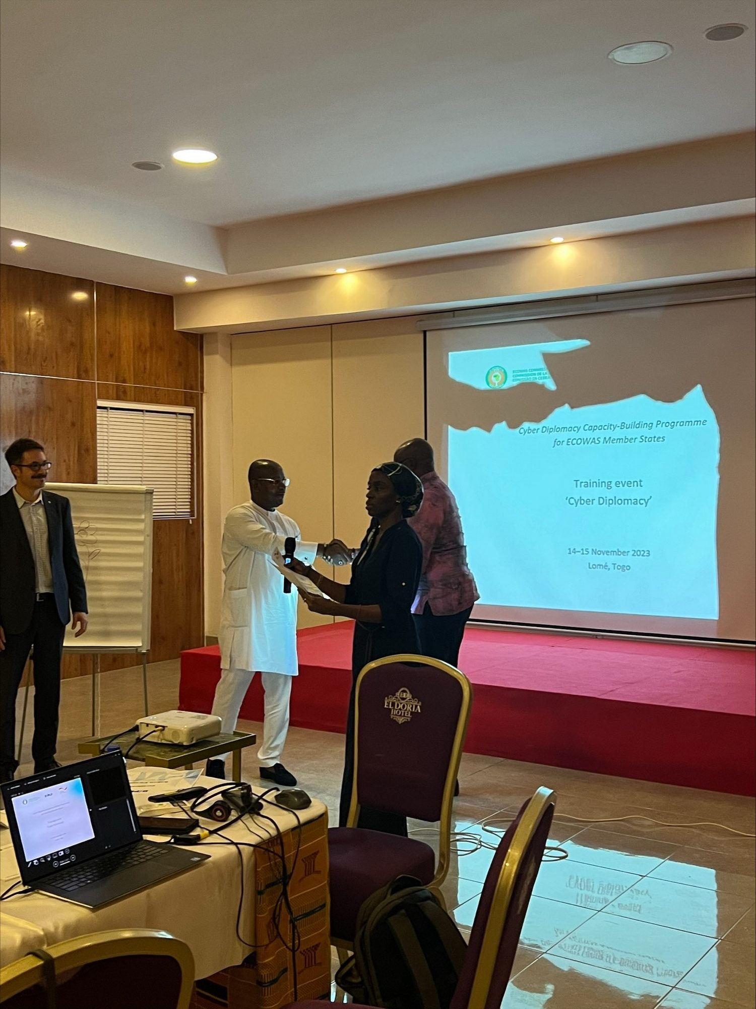  Crowd, Person, Adult, Male, Man, Clothing, Footwear, Shoe, Accessories, Glasses, Female, Woman, Computer, Electronics, Laptop, Pc, Audience, Coat, Speech, Computer Hardware, Hardware, Monitor, Screen, Backpack, Bag, Chair, Furniture