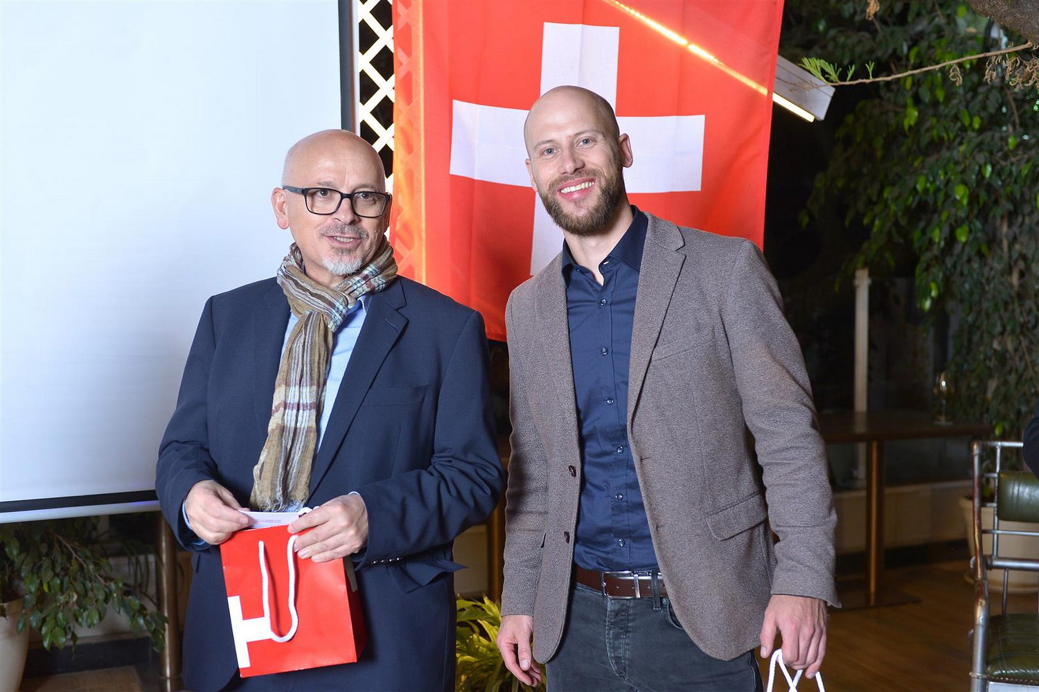  Adult, Male, Man, Person, Blazer, Clothing, Coat, Jacket, Scarf, Jeans, Pants, Face, Head, Accessories, Glasses, People, Chair, Furniture, Flag