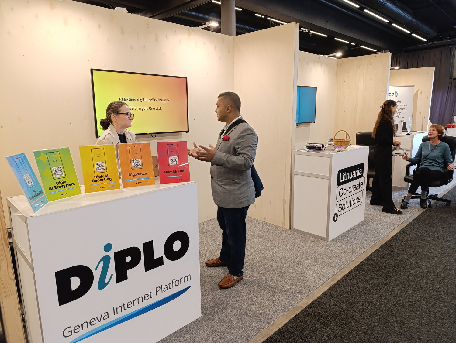 Diplo/GIP at IGF 2025 3 Adult, Female, Person, Woman, Advertisement, Male, Man, Crowd, Computer Hardware, Electronics, Hardware, Monitor, Screen, Clothing, Footwear, Shoe, Accessories, Glasses, Box, Poster, Audience, Coat, Head, Face, Lisa Badum