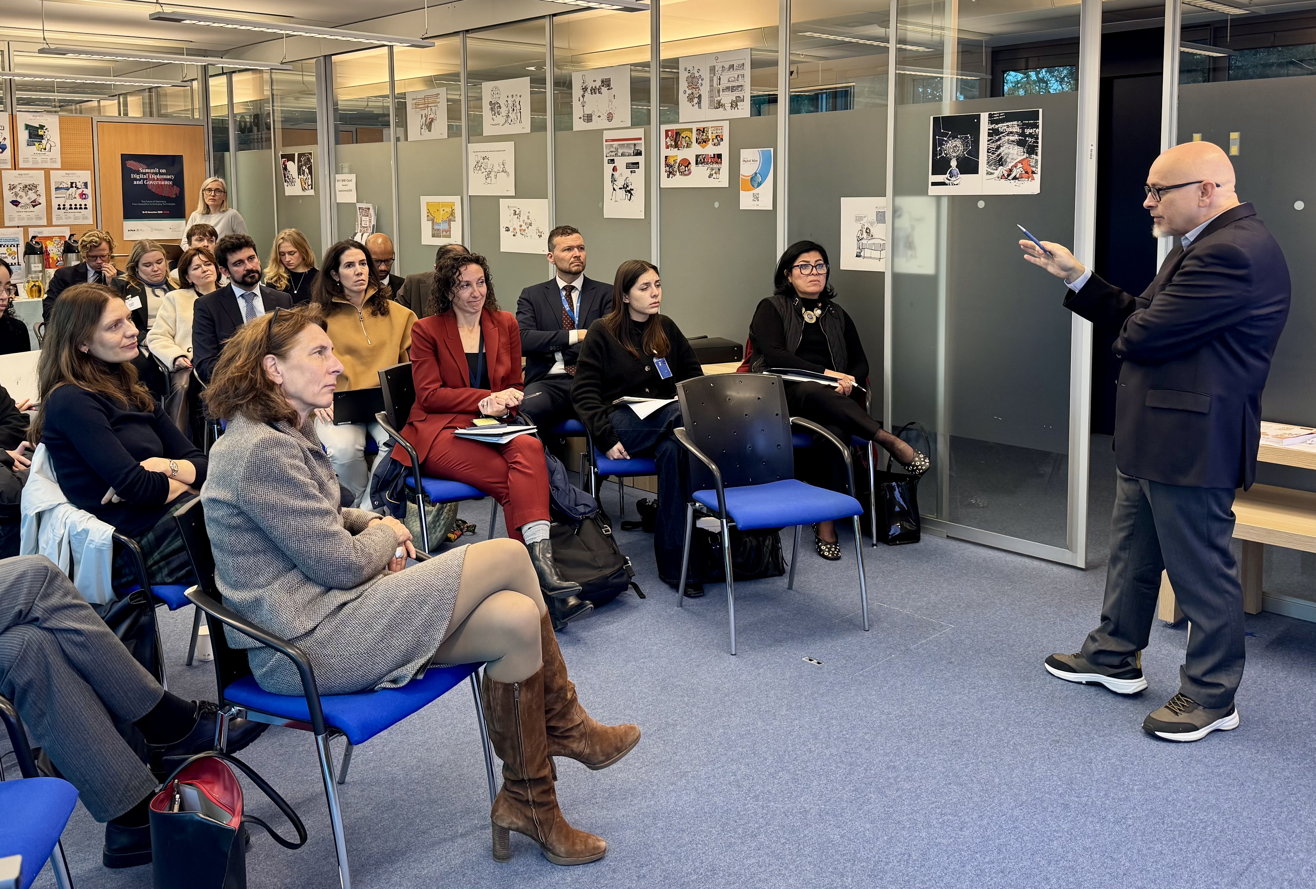  Adult, Female, Person, Woman, Clothing, Footwear, Shoe, Crowd, Accessories, Bag, Handbag, Chair, Furniture, Male, Man, Glasses, Audience, Indoors, Wristwatch, Electronics, Mobile Phone, Phone, Speech, Formal Wear, Suit, Lamp, Sandal, Jewelry, Necklace, Ralf König, Alexis Georgoulis, Cyrille Diabaté, Oleg Kononenko, Jolyon Palmer, Claude Chirac
